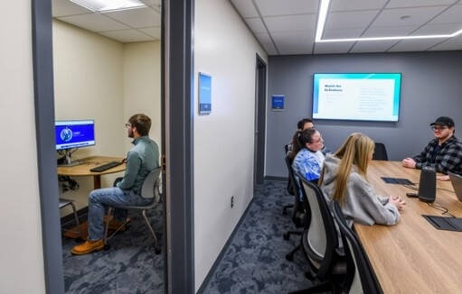 Students sitting at table in small group room while another student sits independently in the individual testing room